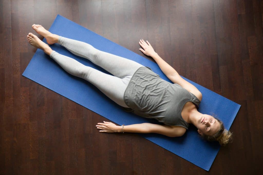 femme qui se repose sur un tapis de yoga