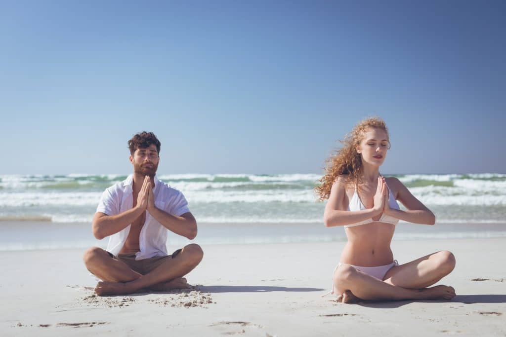 Couple sur la plage en méditation pleine conscience